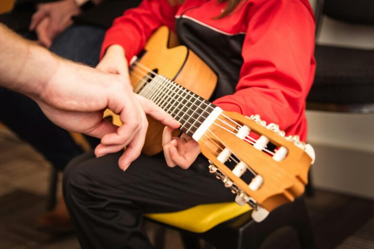 Child receiving guitar lesson with instructor's guidance in Victoria, BC. Focused on strings and technique.