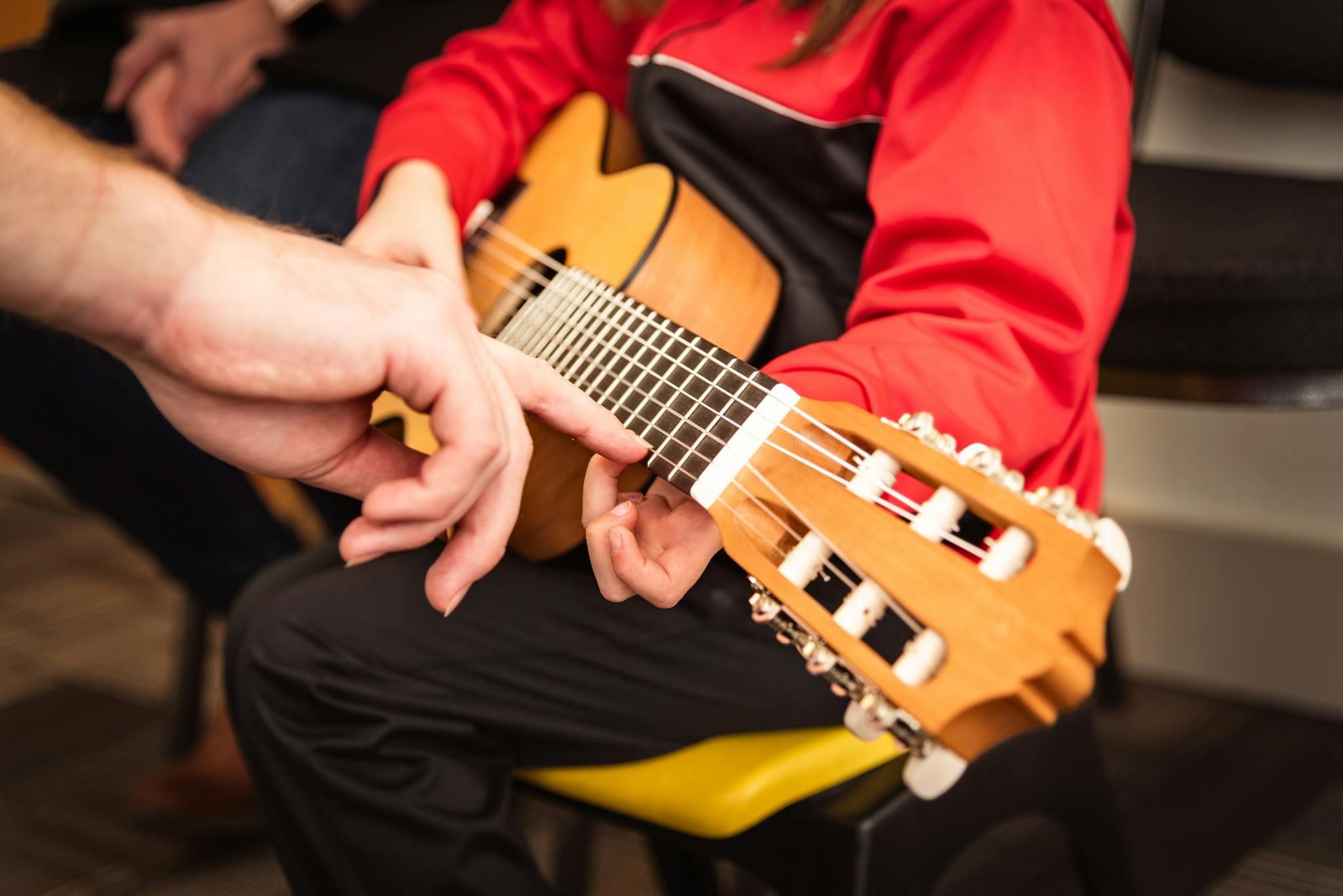 Child receiving guitar lesson with instructor's guidance in Victoria, BC. Focused on strings and technique.