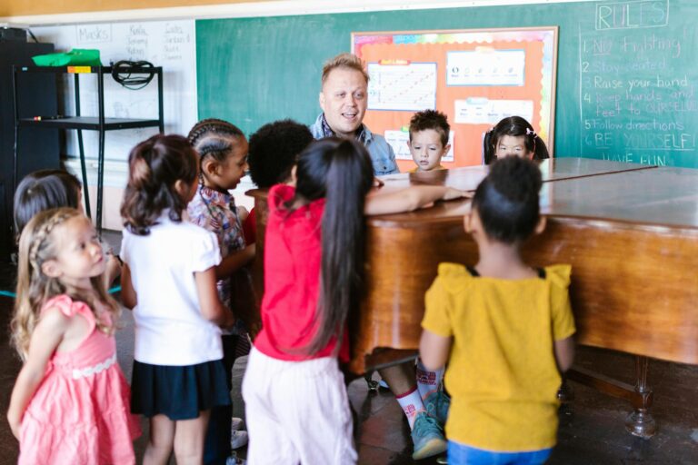 Teacher guiding children in music class around a piano, fostering creativity and diversity.